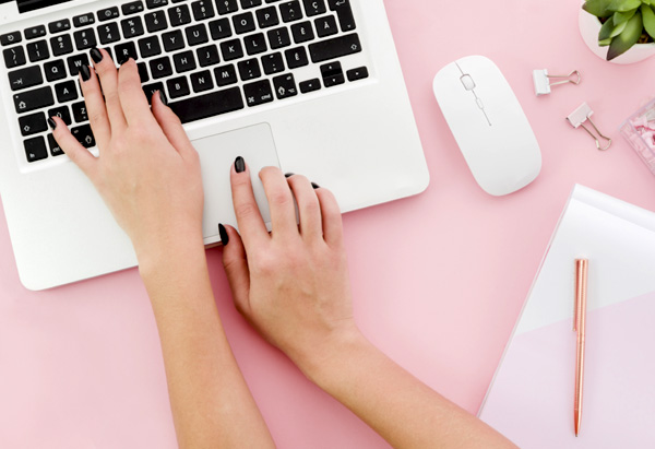 Mains de femme tapant sur le clavier de son ordinateur